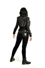 full length portrait of black haired girl wearing leather outfit. standing pose  view from behind,...