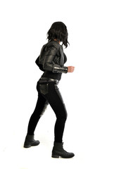 full length portrait of black haired girl wearing leather outfit. standing pose  view from behind, on a white background