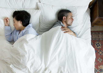 Interracial couple sleeping back to back on the bed