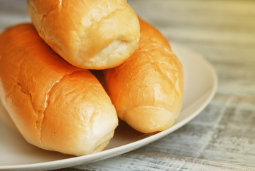 Fresh Buns fot hit Dogs in a White Plate on a Wooden Surface. close Up with Copy Space.