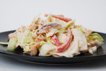 Fresh Russian Vegetable Salad Dressed with Mayonnaise. Black Plate. Isolated on White Background.