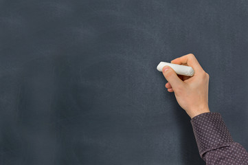 Man with chalk is writing on blackboard