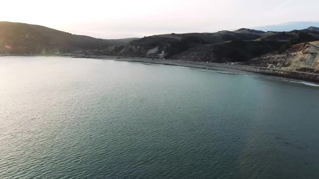 Drone Flyover - Flying from ocean to coastal road on shore at sunset