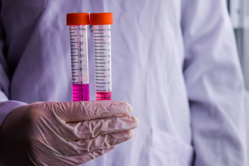 A woman holding test tubes containing purple sample 2
