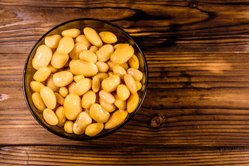 White marinated haricot beans in glass bowl on a wooden table. Top view