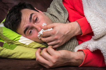 Sick man having flu and blowing her runny nose