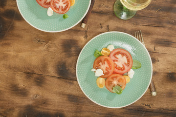 Salad tomatoes mozzarella cheese wooden table white wine, top view