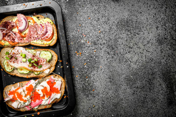 Sandwiches with meat, salami, seafood and fresh vegetables.