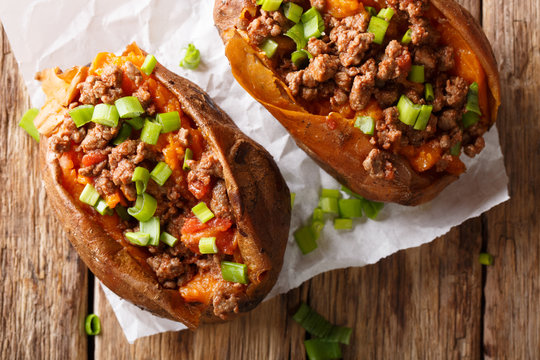 Fototapeta Organic food: baked sweet potato stuffed with ground beef and green onion close-up on paper. horizontal top view