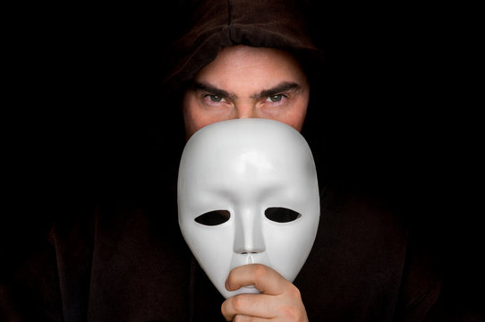 Mysterious man in black hiding his face behind white mask Stock Photo |  Adobe Stock