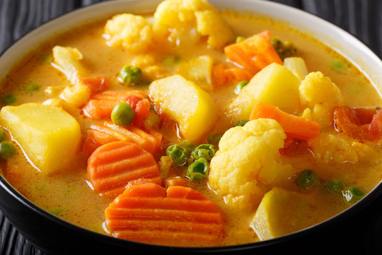 Vegetable curries of potatoes, carrots, cauliflowers, peas, tomatoes close-up in a bowl on the table. horizontal