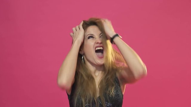 Attractive woman screaming in panic with her hands to her head, mouth open and frightened wide eyes.