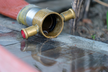 water flows out of Fire hose with reflection in water on the rough ground after use