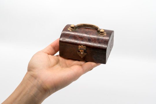 Hand holding vintage luxury wooden box with gold lock and handle isolated on white