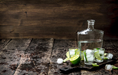 Vodka shots with lime and ice on the board.