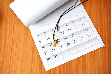 bent white clean sheet of paper monthly calendar with gold personal Christian cross on wooden table, Christmas, new year, the December 2019