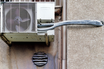 Old probably defective air conditioner and ventilator probably it fan on the exterior wall of an...