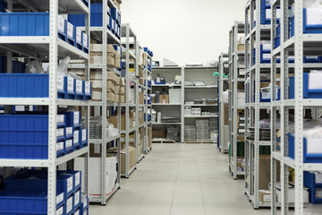 Plastic trays and cardboard boxes in metal racks.