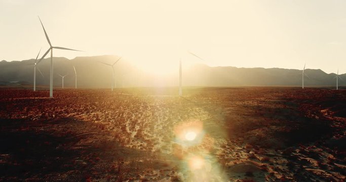 Aerial view of windmills in desert at sunset with lens flare