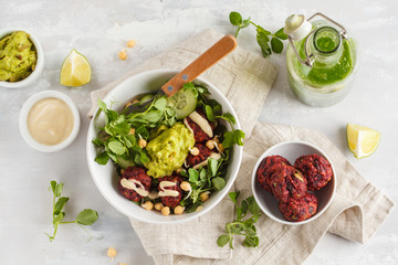 Vegan lunch flat lay. Green vegetable vegan salad with beets meatballs, Guacamole and tahini dressing. Healthy vegetarian food concept. Copy space, top view
