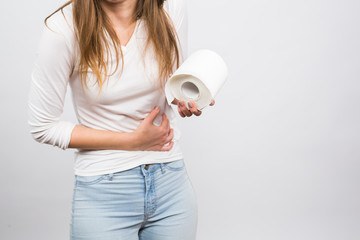 Woman with stomach pain and toilet paper roll on white background