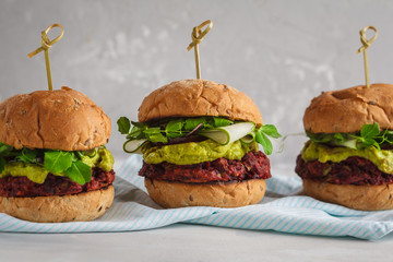 Vegan beet chickpea burgers with vegetables, guacamole and rye buns. Healthy vegan food concept.
