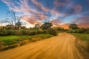 Rural Australian Landscape with colorful clouds ans dirty gravel road in Outback of Australia at sunrise/sunset