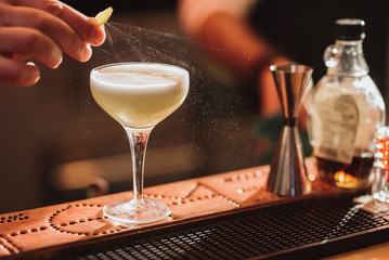 Barman preparing a cocktail with a lemon spray