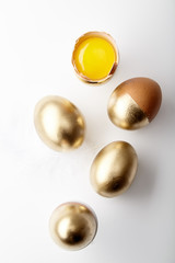 Eggs painted golden with yolk in egg stand on white background. Easter concept, copy space