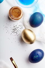 Eggs painted blue and golden colors on Easter holiday. White background, copy space, flatlay composition