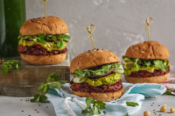 Vegan beet chickpea burgers with vegetables, guacamole and rye bun with green smoothie. Healthy vegan food concept.