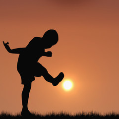 Fototapeta na wymiar Silhouette of boy playing football with the sun