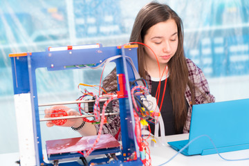 Girl schoolgirl with a 3D printer