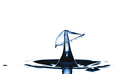 Splash and crown on rippled blue liquid or water surface . Water splash with a crown and reflection