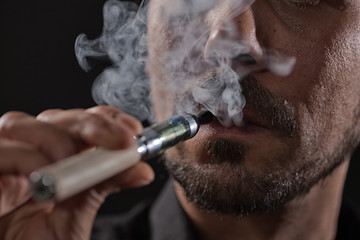 Close up image of man who is smoking electronic cigarette. 