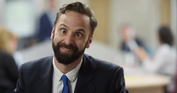 4K Close up portrait businessman turning on his chair to pull a face at camera. Slow motion.