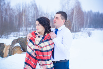 Romantic couple in love the plaid in winter forest, valentine day. Rustic simple Wedding at winter.  Couple Lovers Sensitive, Wrapped in Plaid. 