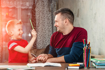 The father and his little son fool around doing homework for the school.