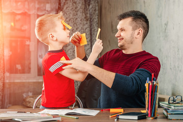 The father and his little son fool around doing homework for the school.