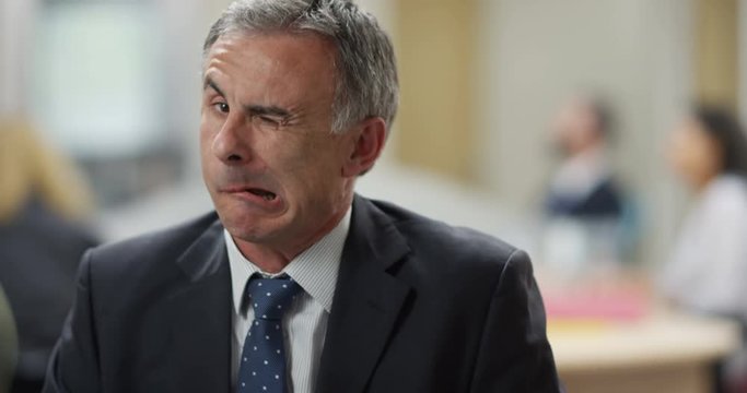 4K Close up portrait mature businessman turning on his chair to pull a face at camera. Slow motion.