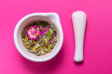Herbs in porcelain mortar on colorful background