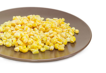Frozen kernels of sweet corn on the brown dish closeup