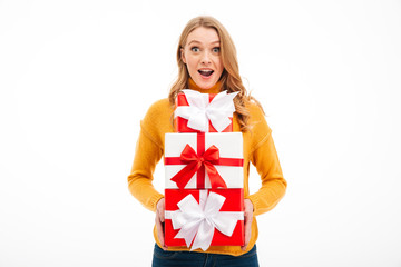 Excited young woman holding surprise gift boxes.