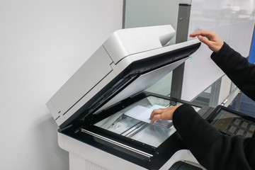 close up businesswoman put documents on printer for scanning and copying in office