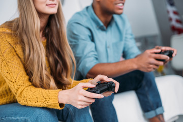 cropped image of multicultural couple playing video game at home