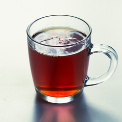 Glass cup of hot black tea on white. Side view. Close up.