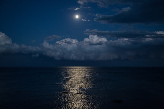 Night sky with full moon and reflection in sea, beautiful clouds.