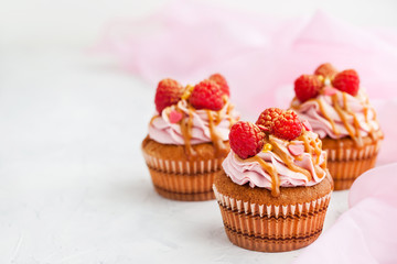 Raspberry and caramel cupcakes on white background