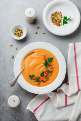Homemade pumpkin soup in white ceramic dish on old gray concrete or stone background. Selective focus.  Top view. Copy space.