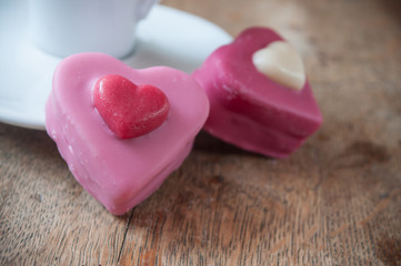 petits four en forme de coeur et tasse à café, sur table en bois pour la st valentin